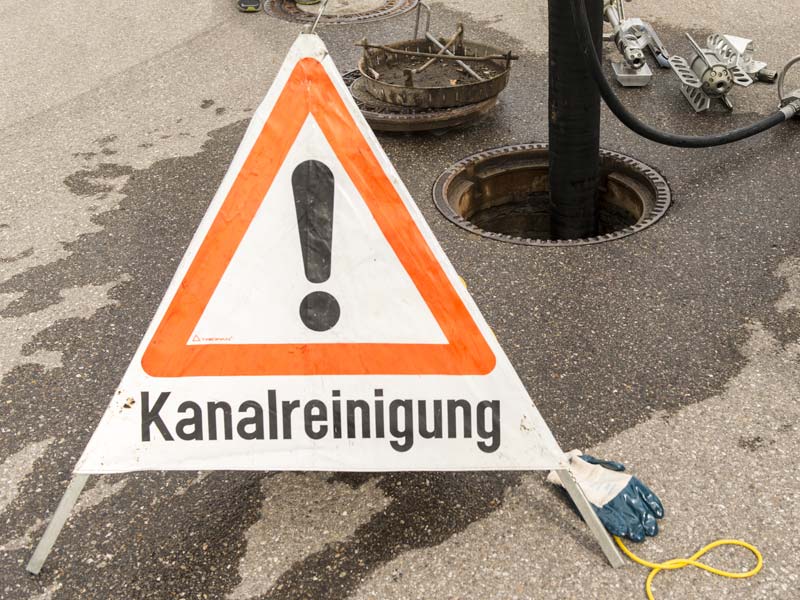 Reinigungsarbeiten an einem geöffneten Schacht